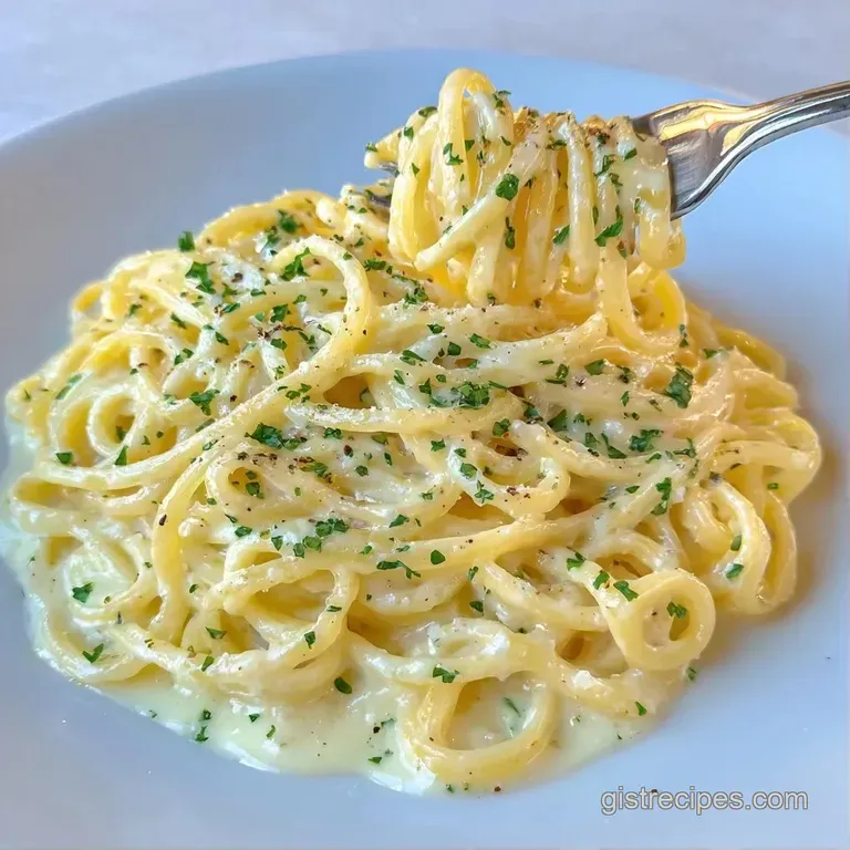 Elegant swirls of pasta topped with snowy parmesan shavings and fresh green herbs on a dark minimalist plate.