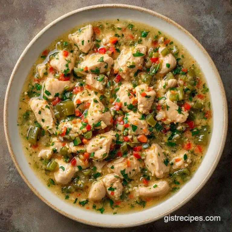 A deep ceramic bowl of creamy white stew garnished with a swirl of sour cream and sliced green scallions.