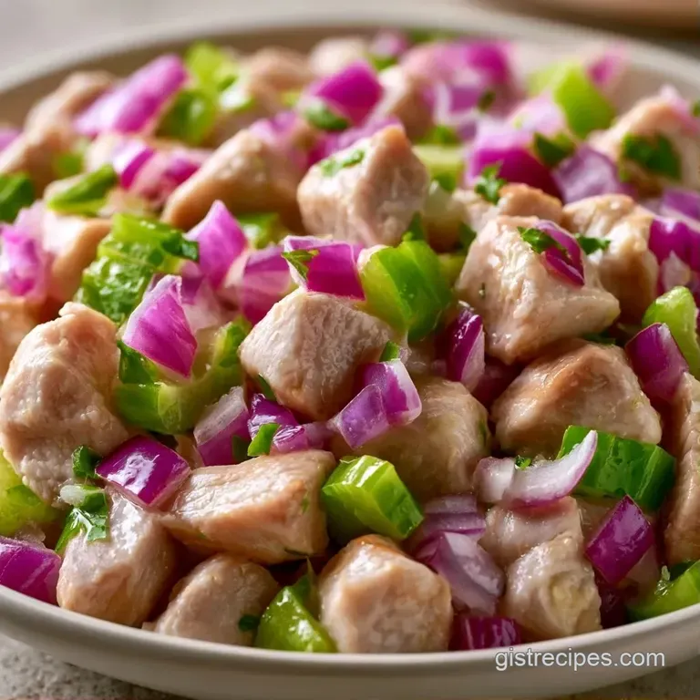 A neatly plated salad with vibrant greens, juicy turkey chunks, and a drizzle of creamy dressing on a white plate.