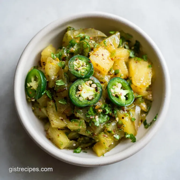 A small ceramic dish brimming with jewel-toned chutney, showcasing pineapple's golden hues and jalapeno's fiery green.