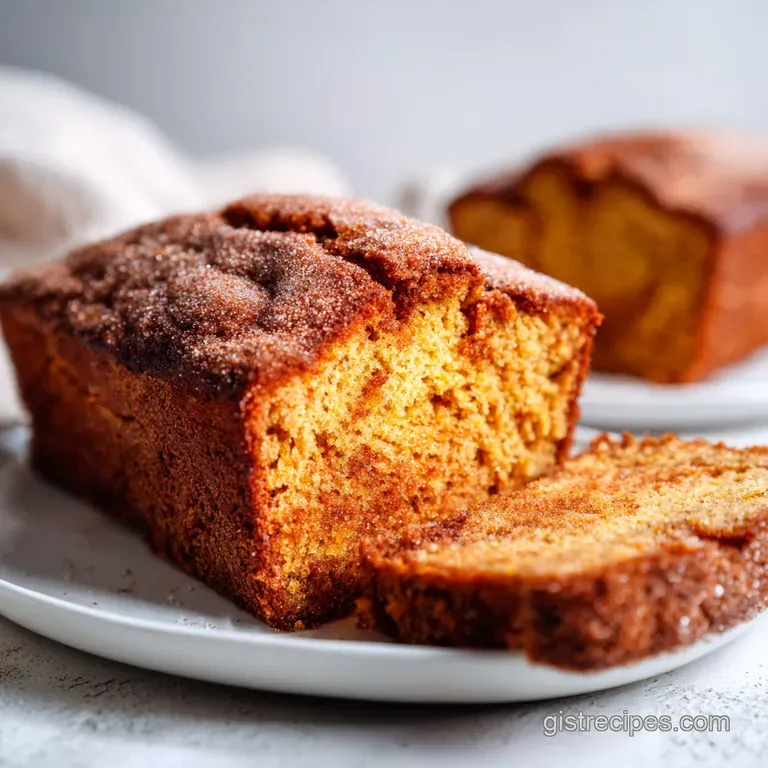A rustic loaf of pumpkin bread with a dusting of cinnamon sugar, artfully sliced on a wooden board.