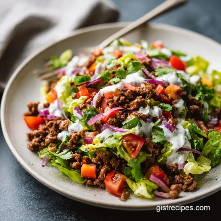 Drizzled taco salad dressing cascading over crisp green lettuce, bright red tomatoes, and seasoned ground beef in a white ...
